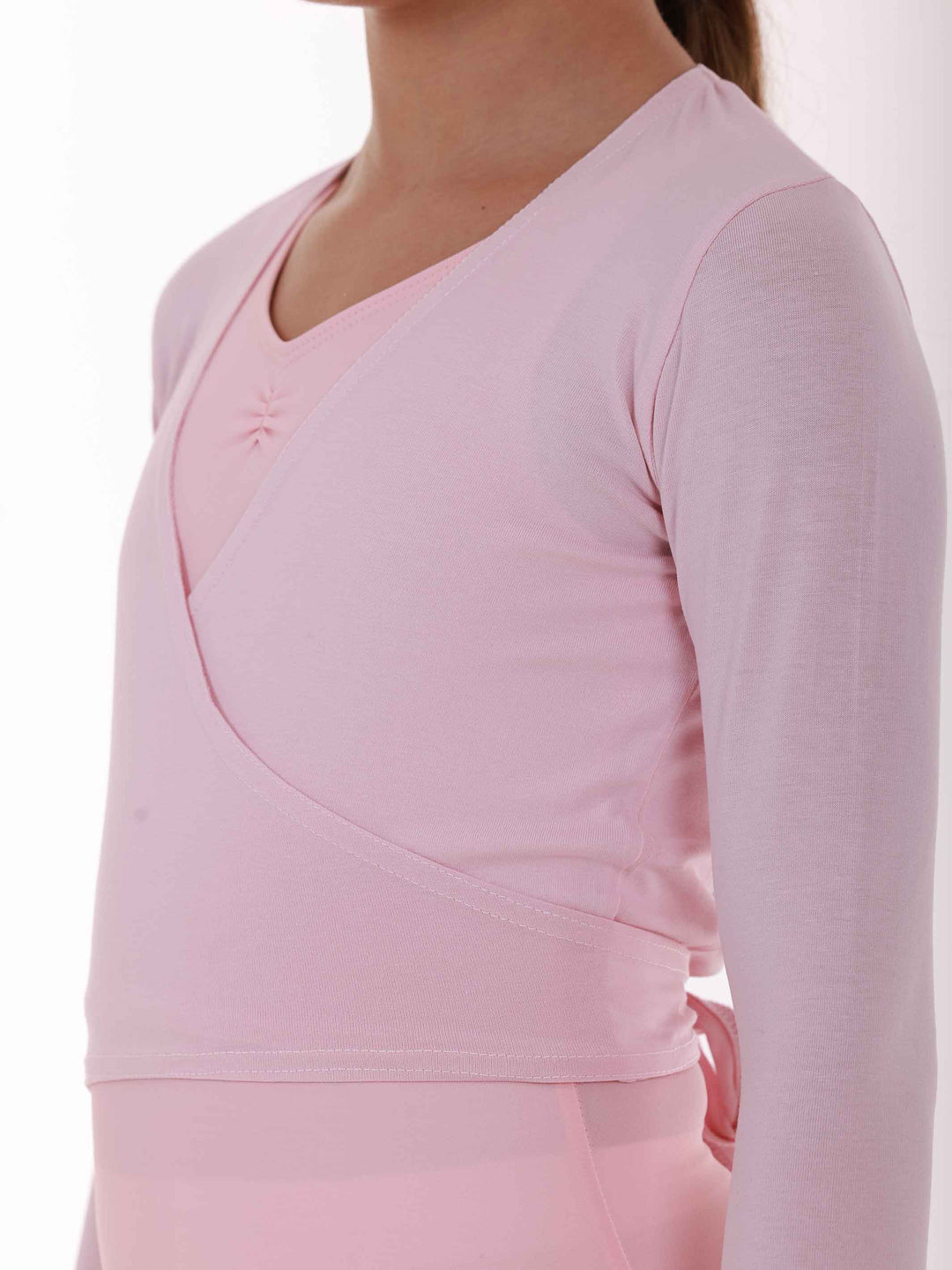 Cache-cœur de ballet pour fille à manches longues, rose clair, avec design croisé et un trou sur le côté droit pour passer la sangle. Équipé de deux longues sangles pour un ajustement parfait et sécurisé, ce cache-cœur offre une couverture optimale tout en garantissant un look élégant. Idéal pour les cours de ballet et autres activités de danse - gros plan de la vue de côté