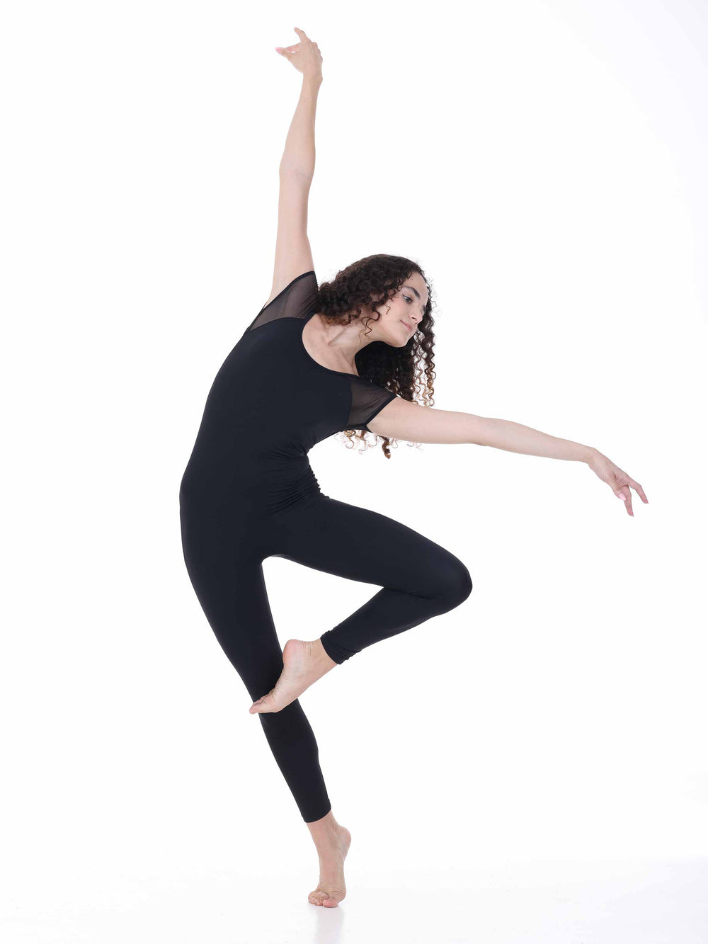 Danseuse portant la combinaison de danse Sway – modèle Sheer Cap Sleeve Dance Unitard en noir, exécutant une pose de danse moderne avec un bras levé, sur fond blanc.