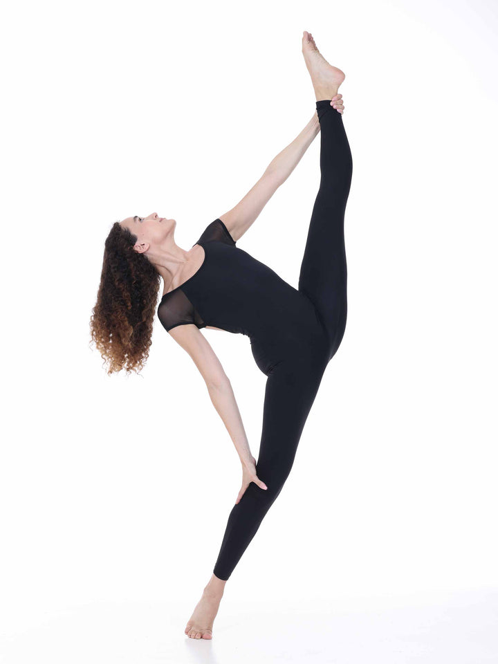Danseuse portant la combinaison de danse Sway – modèle Sheer Cap Sleeve Dance Unitard en noir, réalisant une extension de jambe haute en position de danse contemporaine, sur fond blanc.