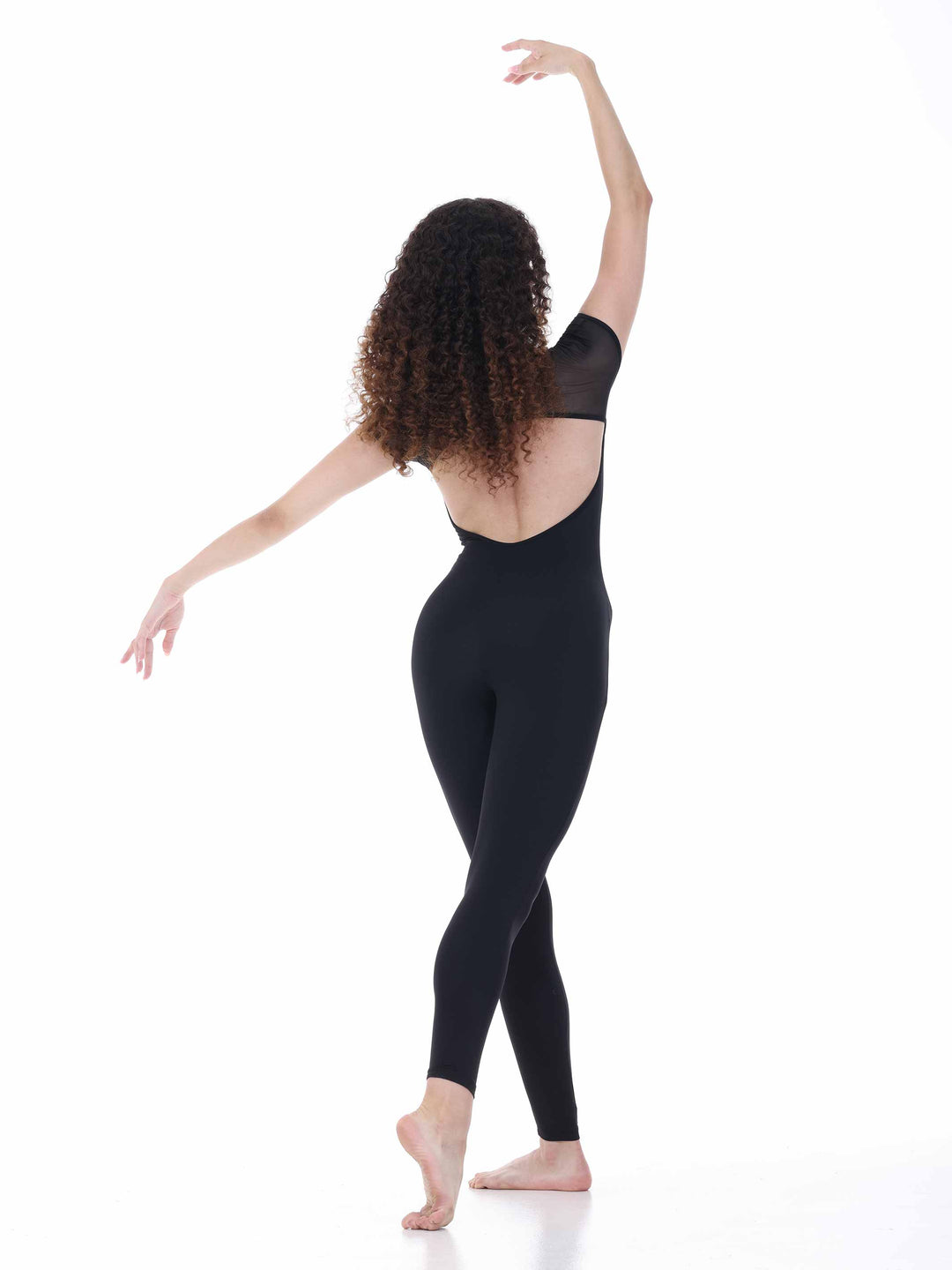 Danseuse vue de dos portant la combinaison de danse Sway – modèle Sheer Cap Sleeve Dance Unitard en noir, mettant en avant le dos échancré et les manches transparentes, sur fond blanc.
