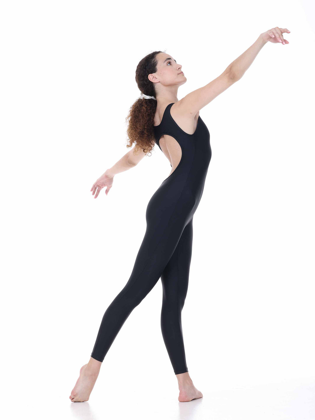 Danseuse portant le justaucorps intégral Sway – modèle Circular Back Tank Dance Unitard en noir, exécutant une pose de danse classique avec les bras levés, sur fond blanc.