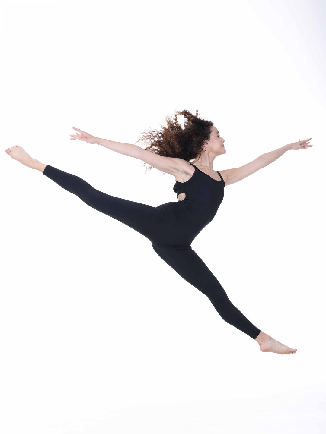 Danseuse en plein saut portant un unitard noir à dos croisé – mouvement aérien en tenue de danse Sway.