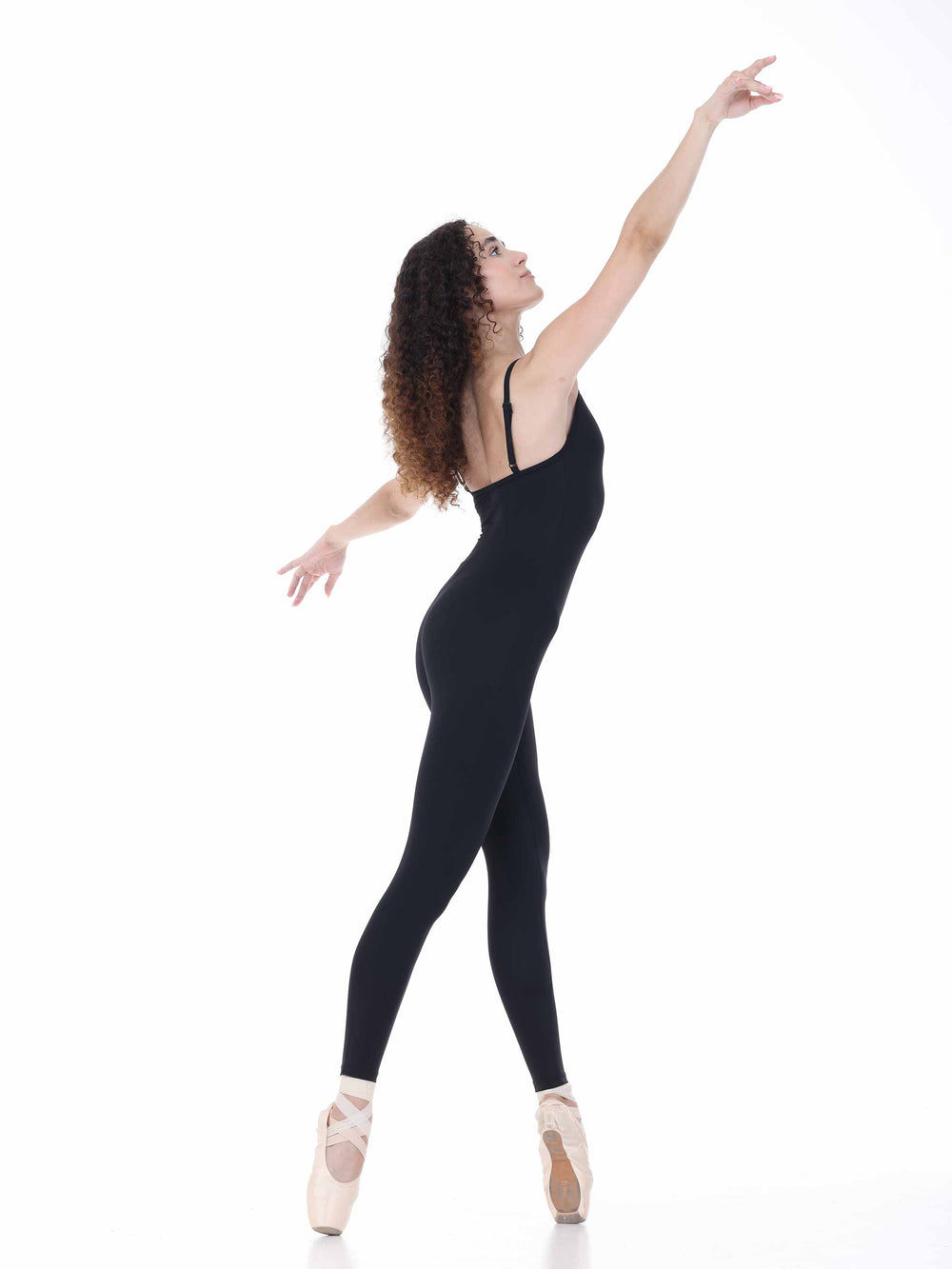 Profil de danseuse en unitard noir ajusté, pose élancée sur pointes – tenue élégante pour danse classique.