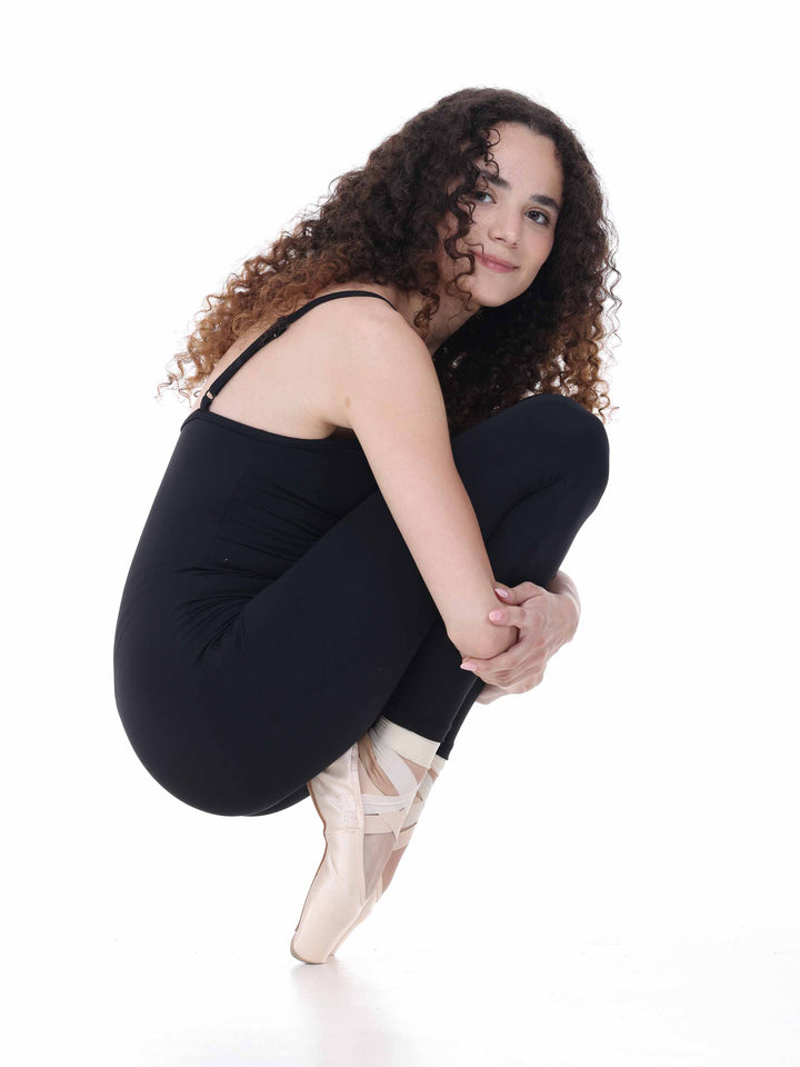 Portrait assis d’une danseuse en unitard noir, ambiance studio – look mode danse contemporaine.