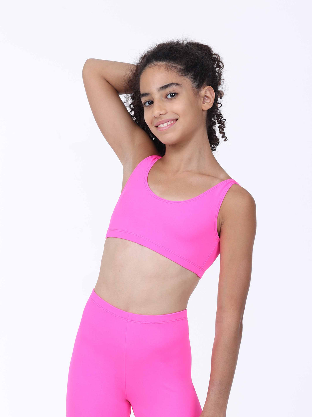 Portrait d’une jeune danseuse portant un ensemble rose vif ajusté – brassière et short assortis.