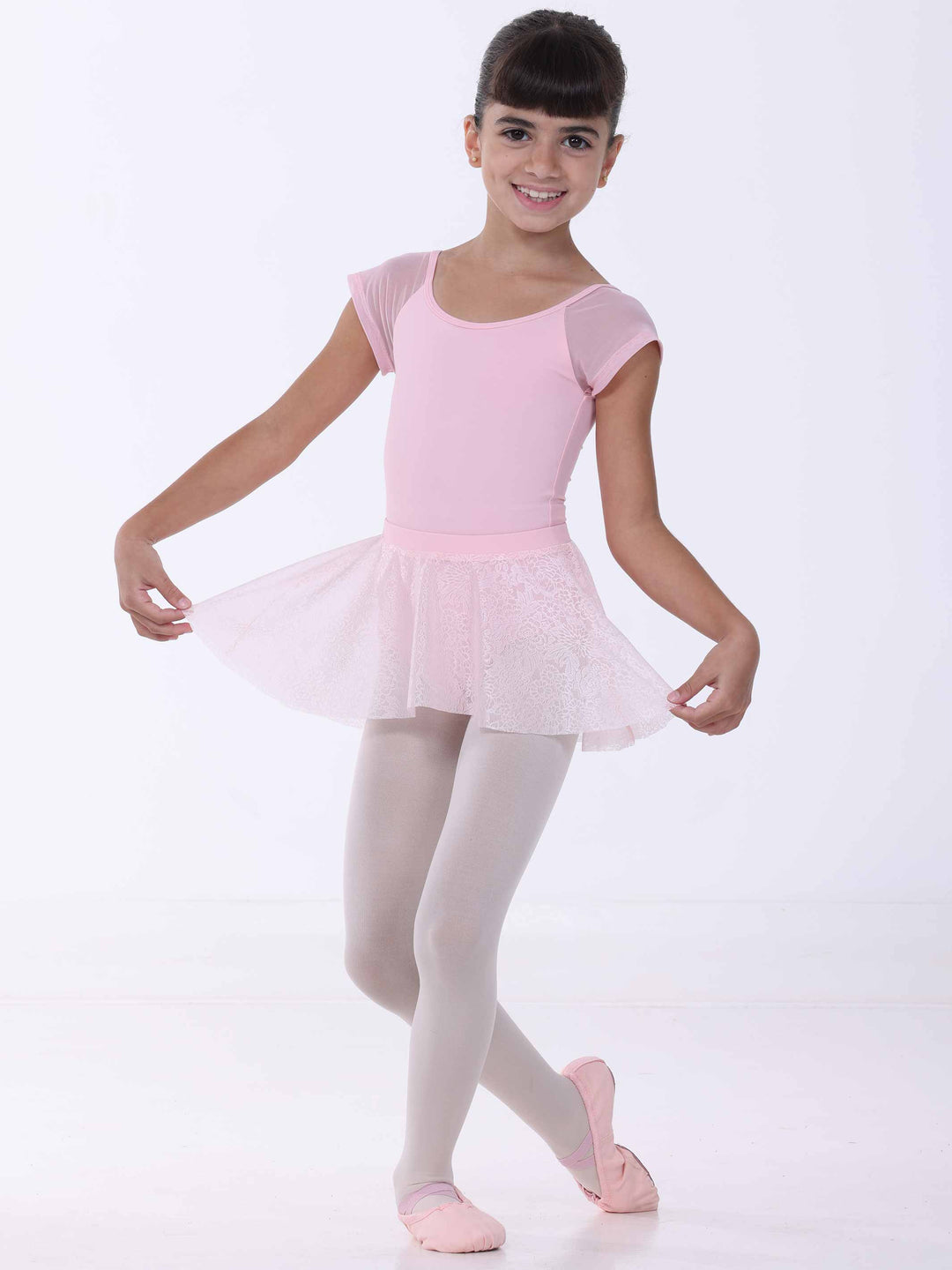 Jeune danseuse portant une jupe de danse rose clair – dentelle florale et mouvement gracieux.
