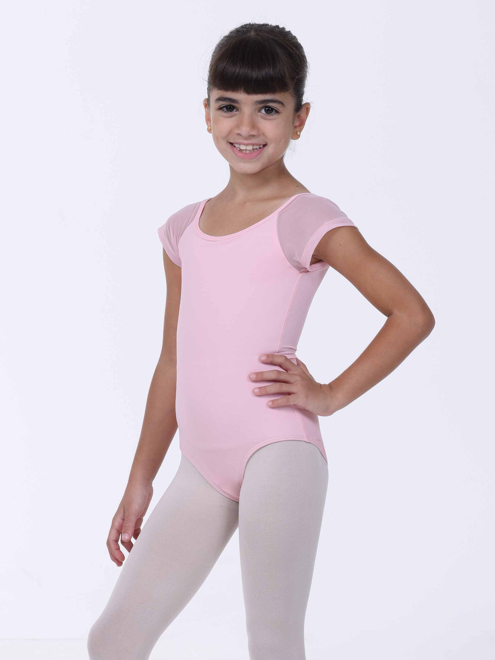 Jeune danseuse souriante portant un justaucorps rose clair – coupe classique et manches en tulle.