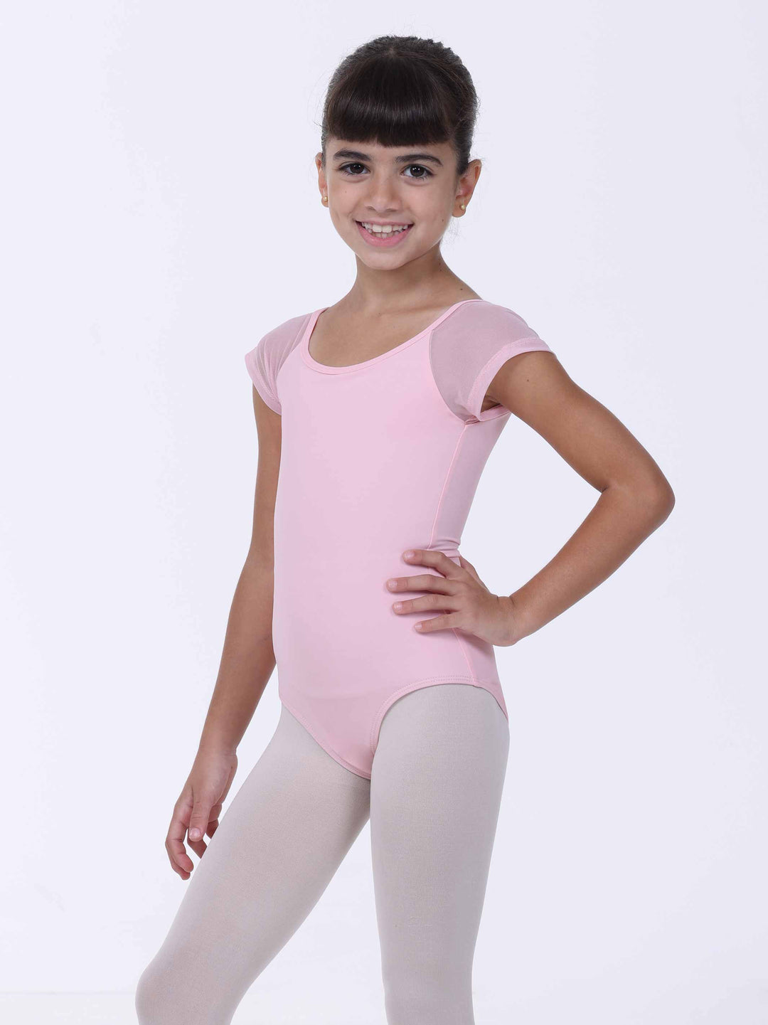 Jeune danseuse souriante portant un justaucorps rose clair – coupe classique et manches en tulle.