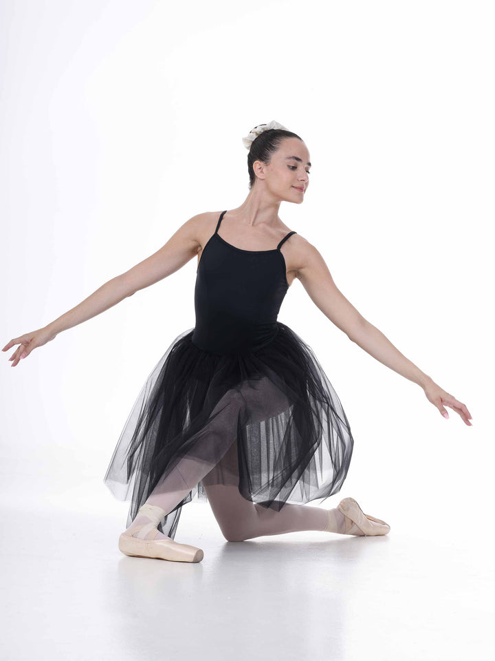 Danseuse en pose classique au sol avec un tutu noir – jupe en tulle souple et allure de scène raffinée.