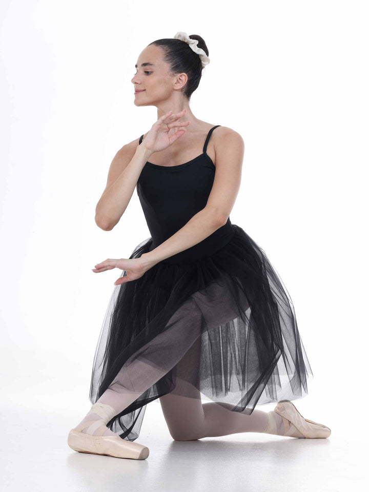 Danseuse en position assise au sol, portant un tutu noir – tissu en tulle transparent et allure poétique.