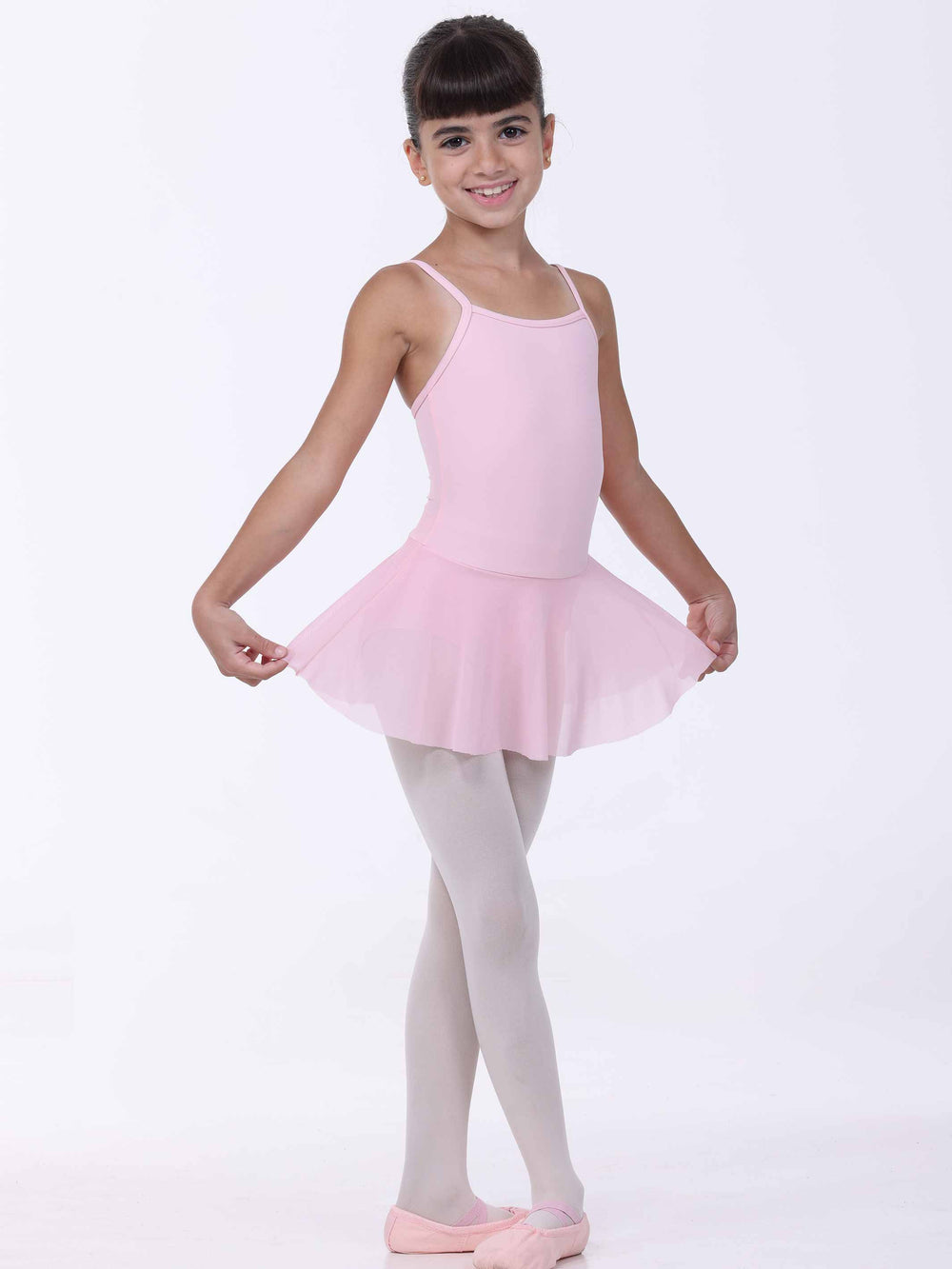 Jeune danseuse souriante portant une robe de danse rose clair – bretelles fines et jupe légère.