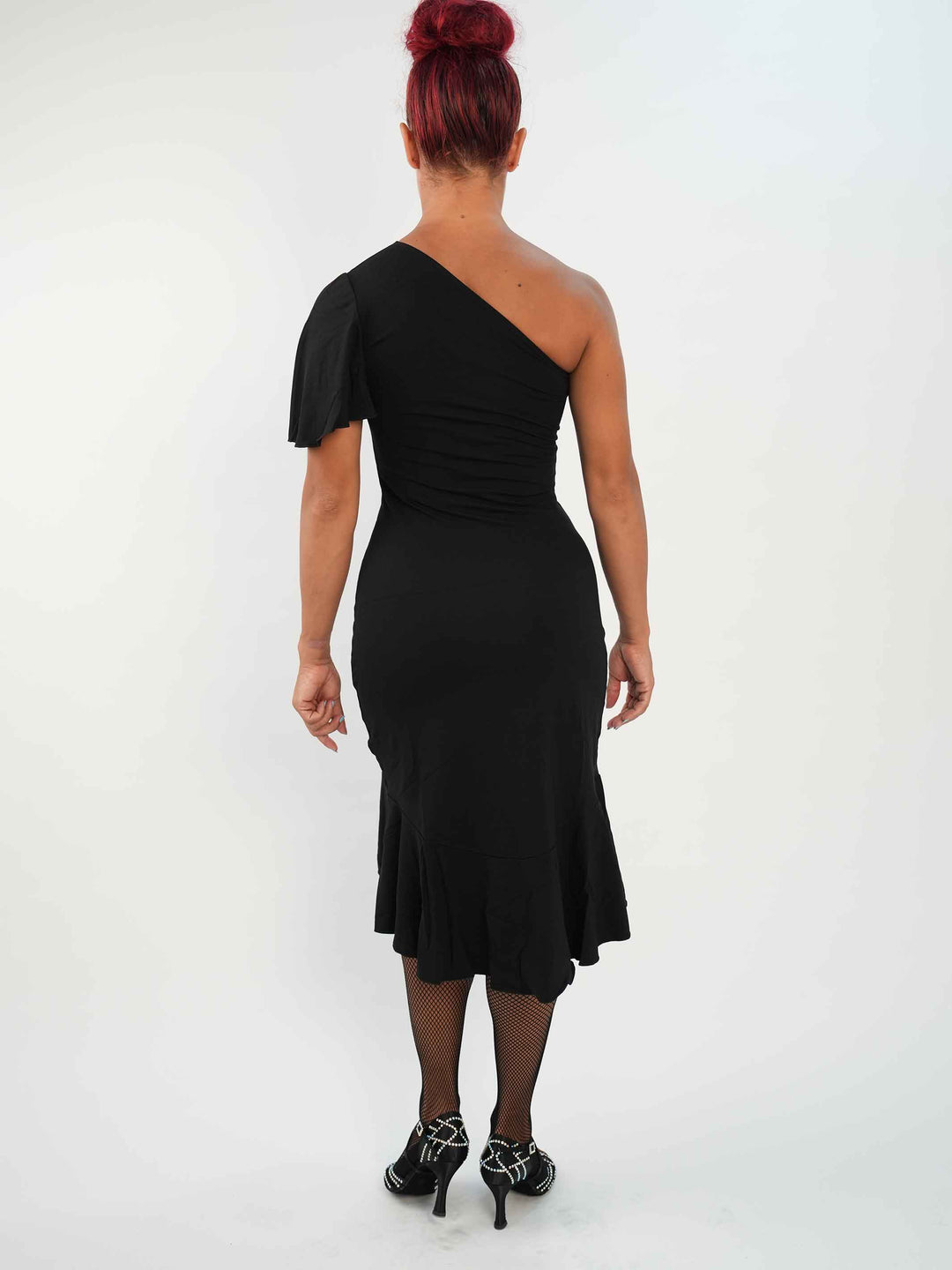 Femme portant une élégante robe latine noire asymétrique avec une manche volante, jupe fluide à godets, idéale pour la salsa, la bachata ou autres danses latines. - vue arrière