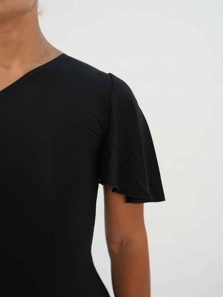 Femme portant une élégante robe latine noire asymétrique avec une manche volante, jupe fluide à godets, idéale pour la salsa, la bachata ou autres danses latines. gros plan