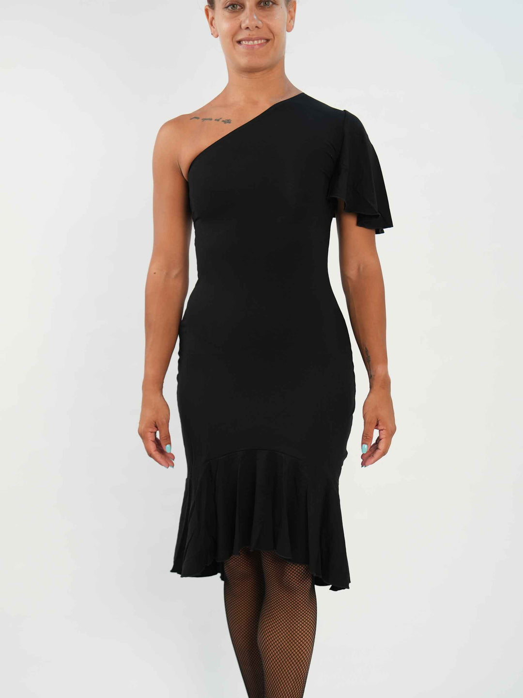 Femme portant une élégante robe latine noire asymétrique avec une manche volante, jupe fluide à godets, idéale pour la salsa, la bachata ou autres danses latines.