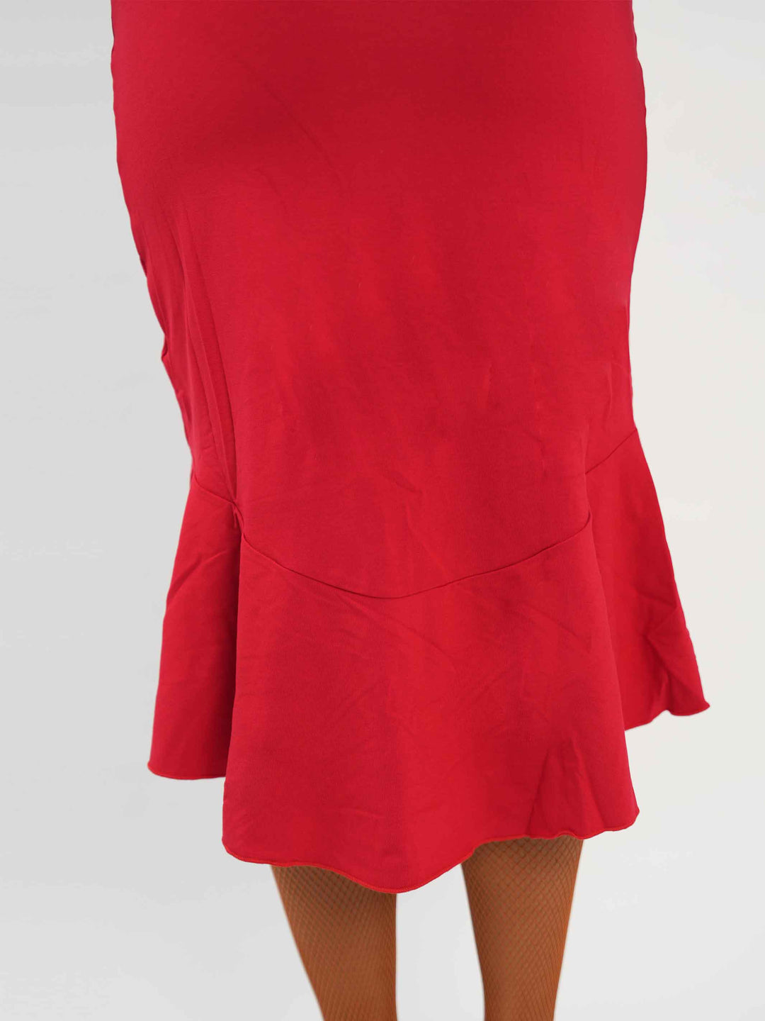 Femme portant une élégante robe latine rouge asymétrique avec une manche volante, jupe fluide à godets, idéale pour la salsa, la bachata ou autres danses latines. - vue de la jupe