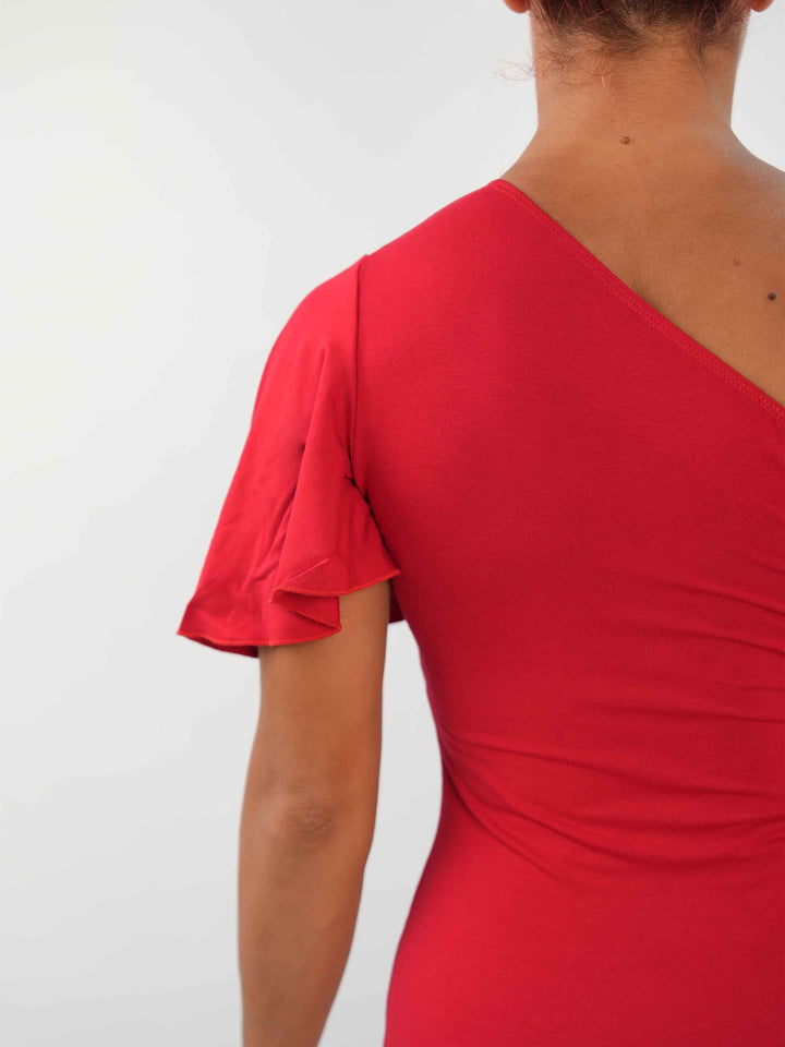 Femme portant une élégante robe latine rouge asymétrique avec une manche volante, jupe fluide à godets, idéale pour la salsa, la bachata ou autres danses latines. - gros plan