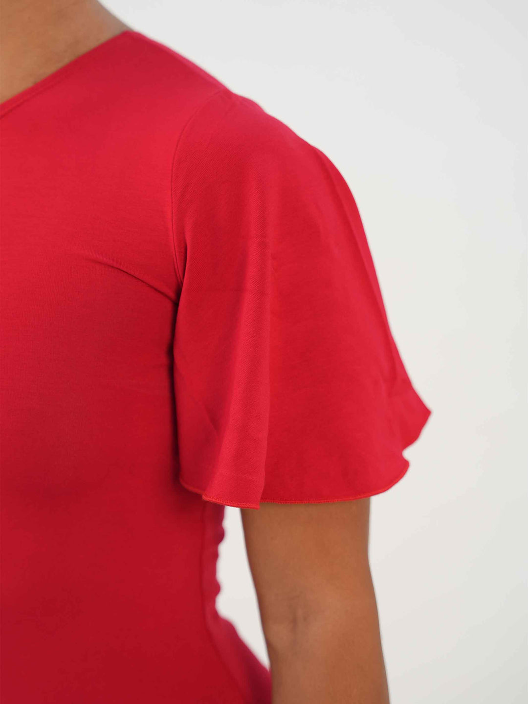 Femme portant une élégante robe latine rouge asymétrique avec une manche volante, jupe fluide à godets, idéale pour la salsa, la bachata ou autres danses latines. - gros plan